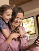 Mother and child on couch browsing cars with smartphone
