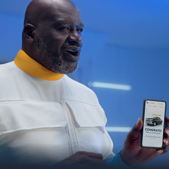 Shaquille O’Neal holding a phone after buying a car on Carvana
